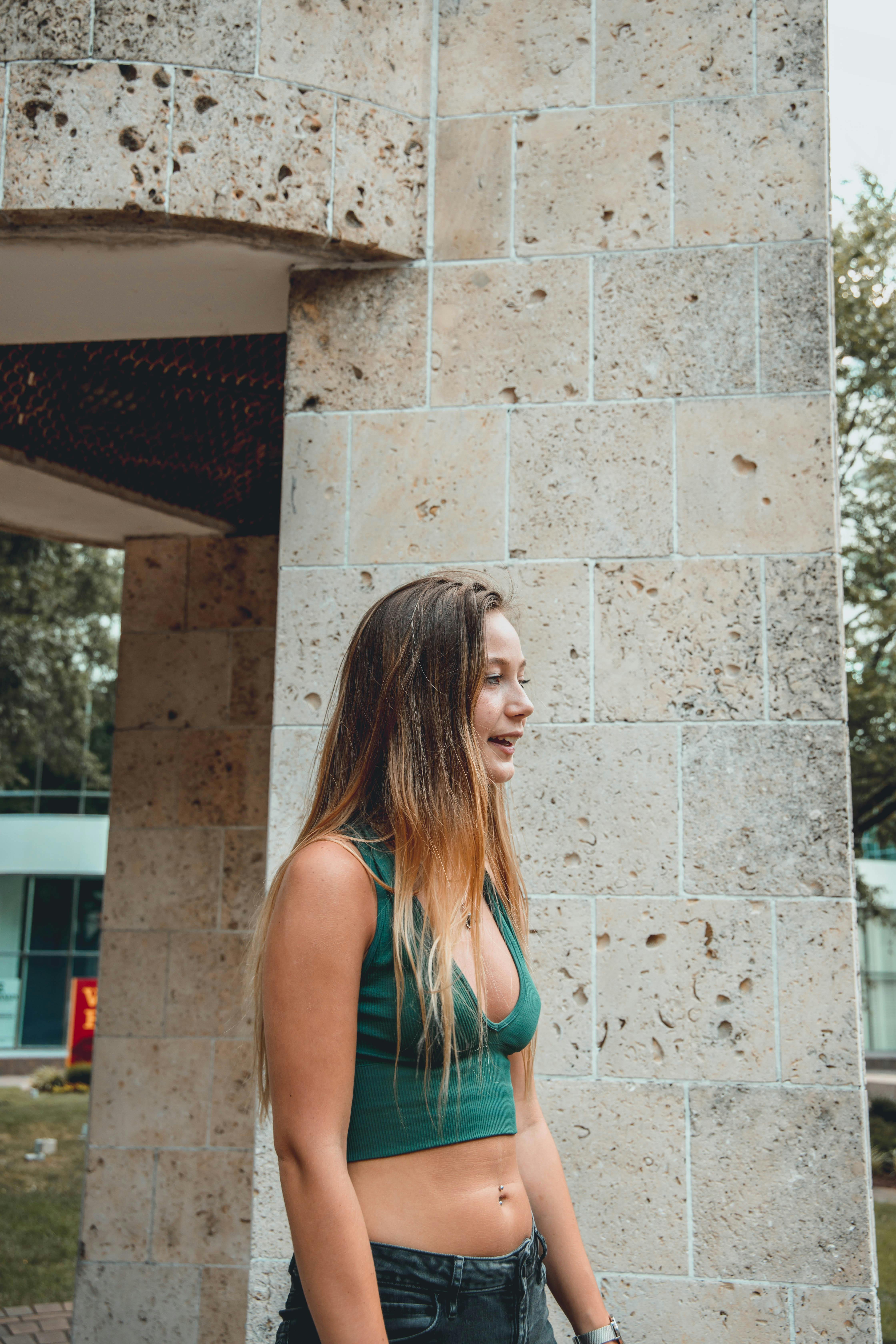 Woman in Blue Tank Top Leaning on White Concrete Wall · Free Stock