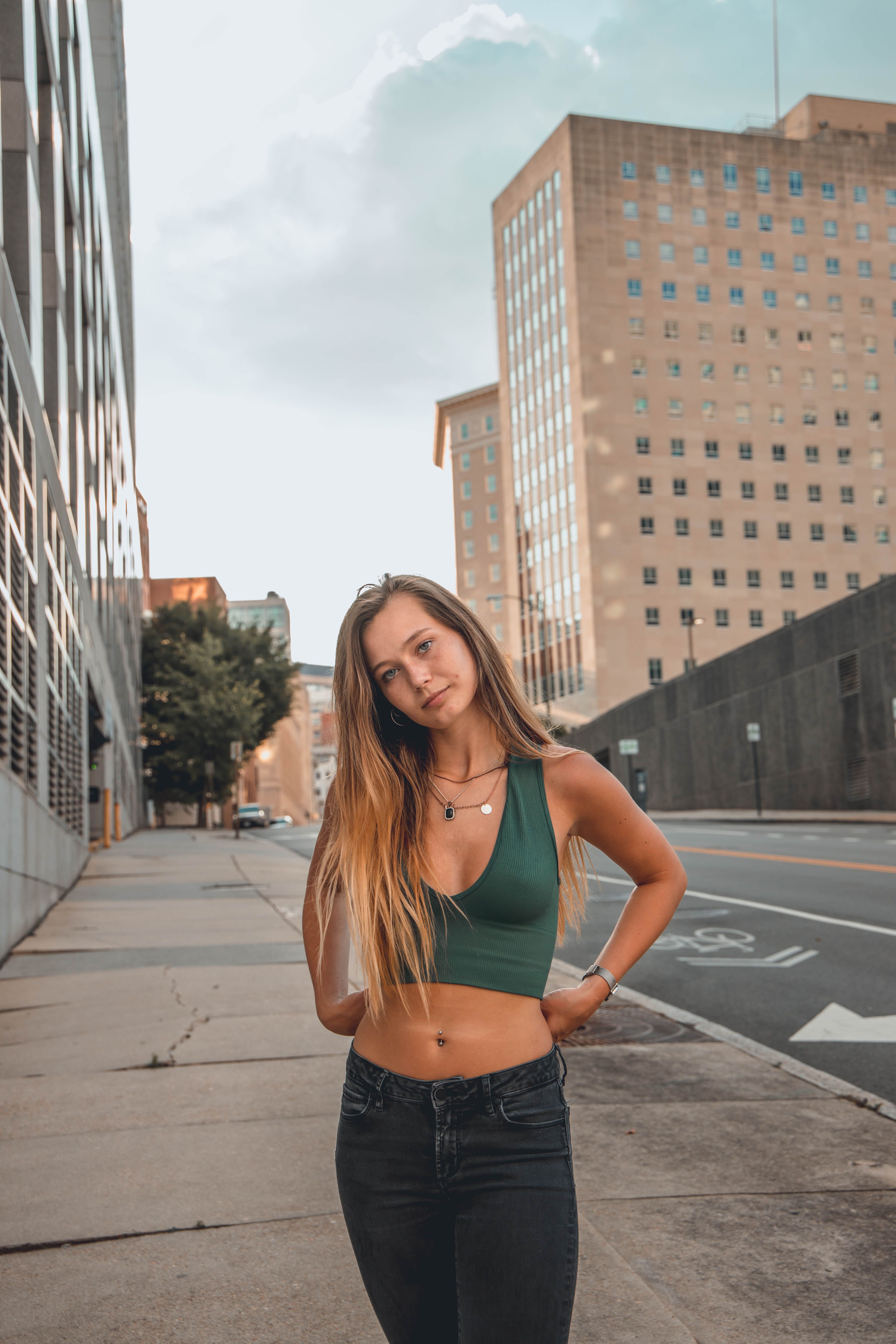 Stylish young woman posing confidently on a city street with modern buildings.