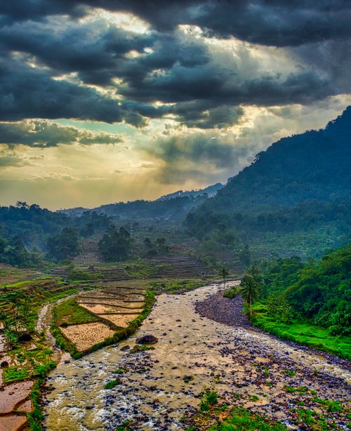 Free Stunning view of rice terraces and river under dramatic skies in West Java, Indonesia. Stock Photo