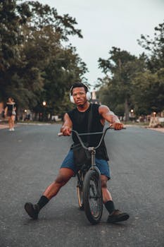 A young man wearing headphones rides a BMX bike on an outdoor road, showcasing urban lifestyle.