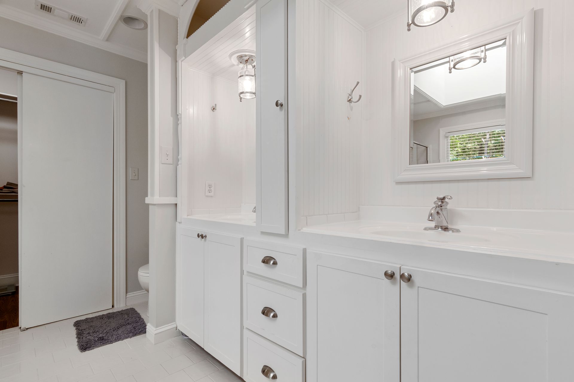 Elegant white bathroom featuring a modern vanity with sleek fixtures and ample storage.
