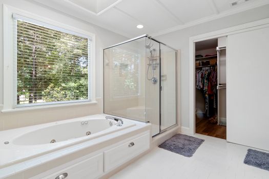 Spacious bathroom featuring a bathtub, glass shower, and walk-in closet.