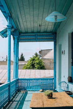 漆成宁静蓝色的阳台，摆放着质朴的桌子和郁郁葱葱的绿色植物