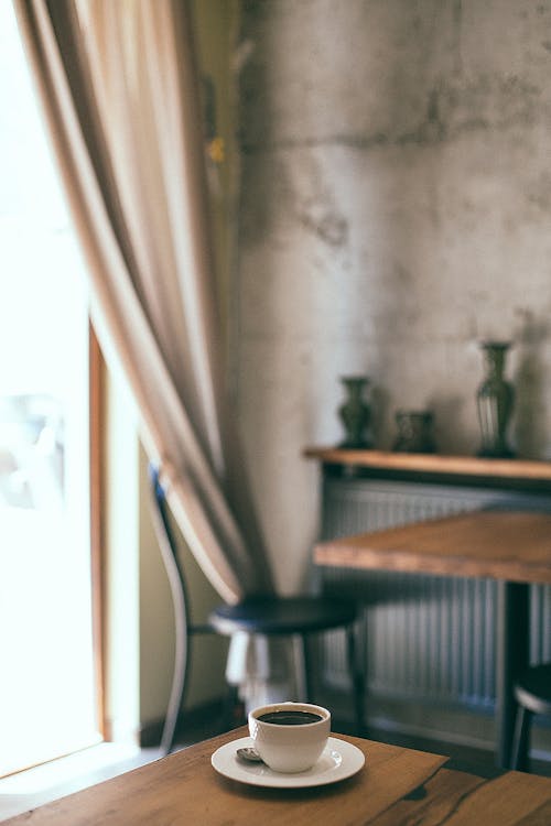 Free From above of cup of aromatic coffee placed on wooden table in cozy classic styled cafe on sunny day Stock Photo