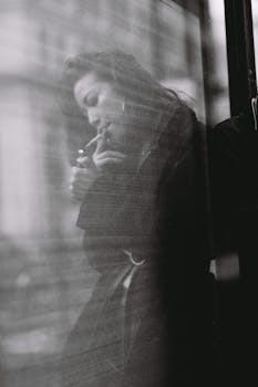 透过城市环境中的玻璃反射，一名女子在黑白照片中吸烟