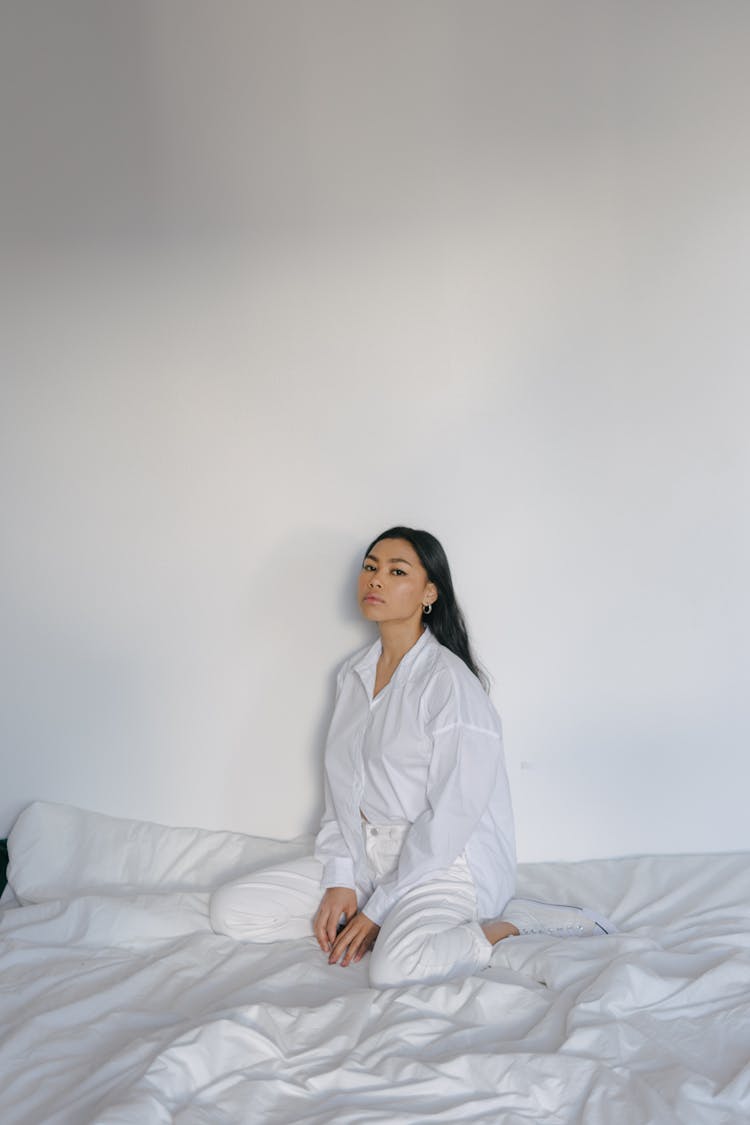 Confident Young Asian Female Relaxing On Comfortable Bed At Home