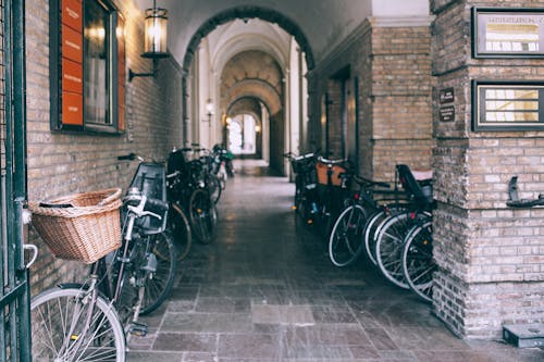 Various bicycles parked near brick walls of arched passage on old city street in daytime