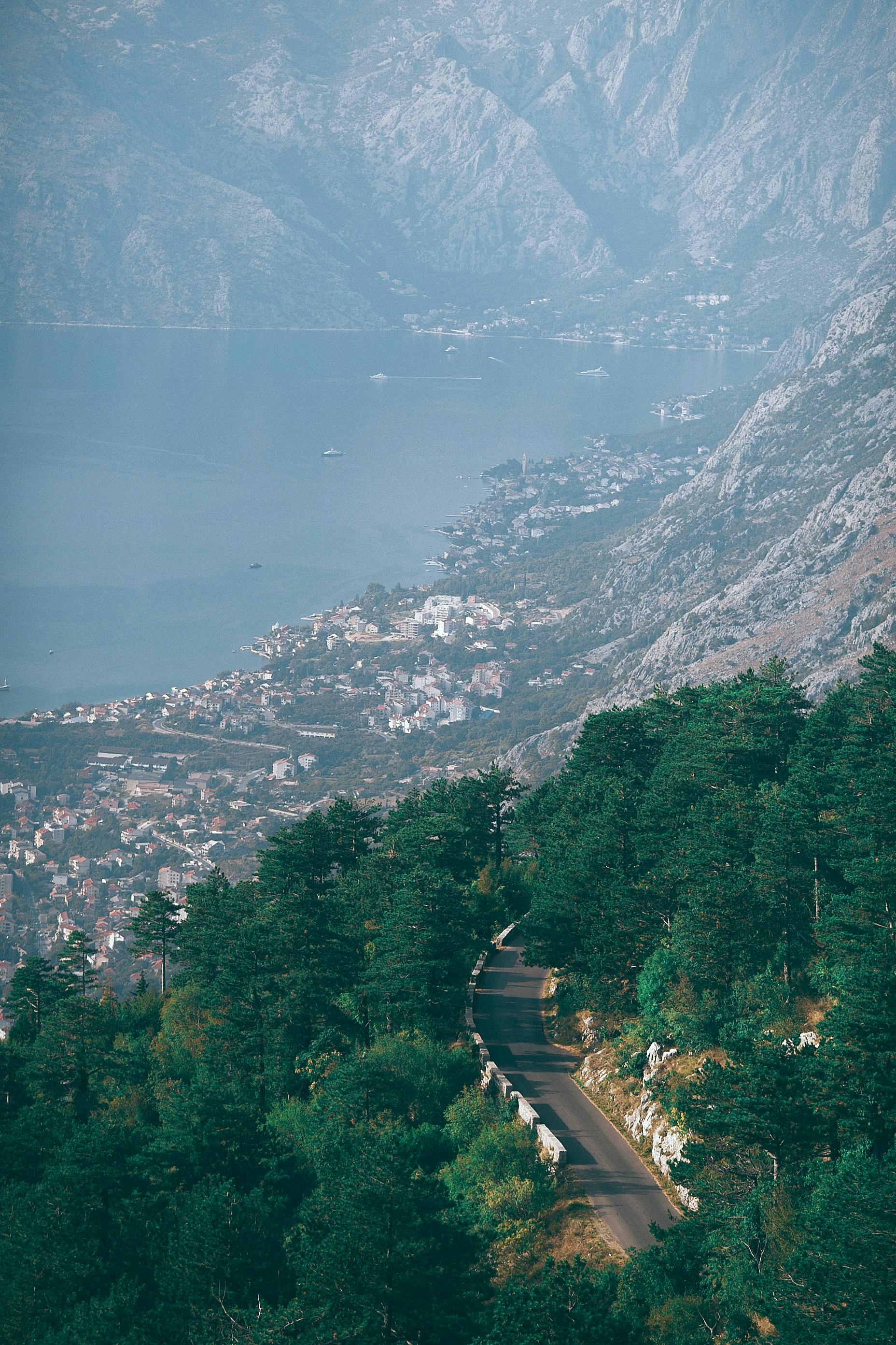 一条狭窄的柏油路穿过郁郁葱葱的绿树，通往海滨小镇，四周环绕着巨大的岩石山脉，景色壮丽
