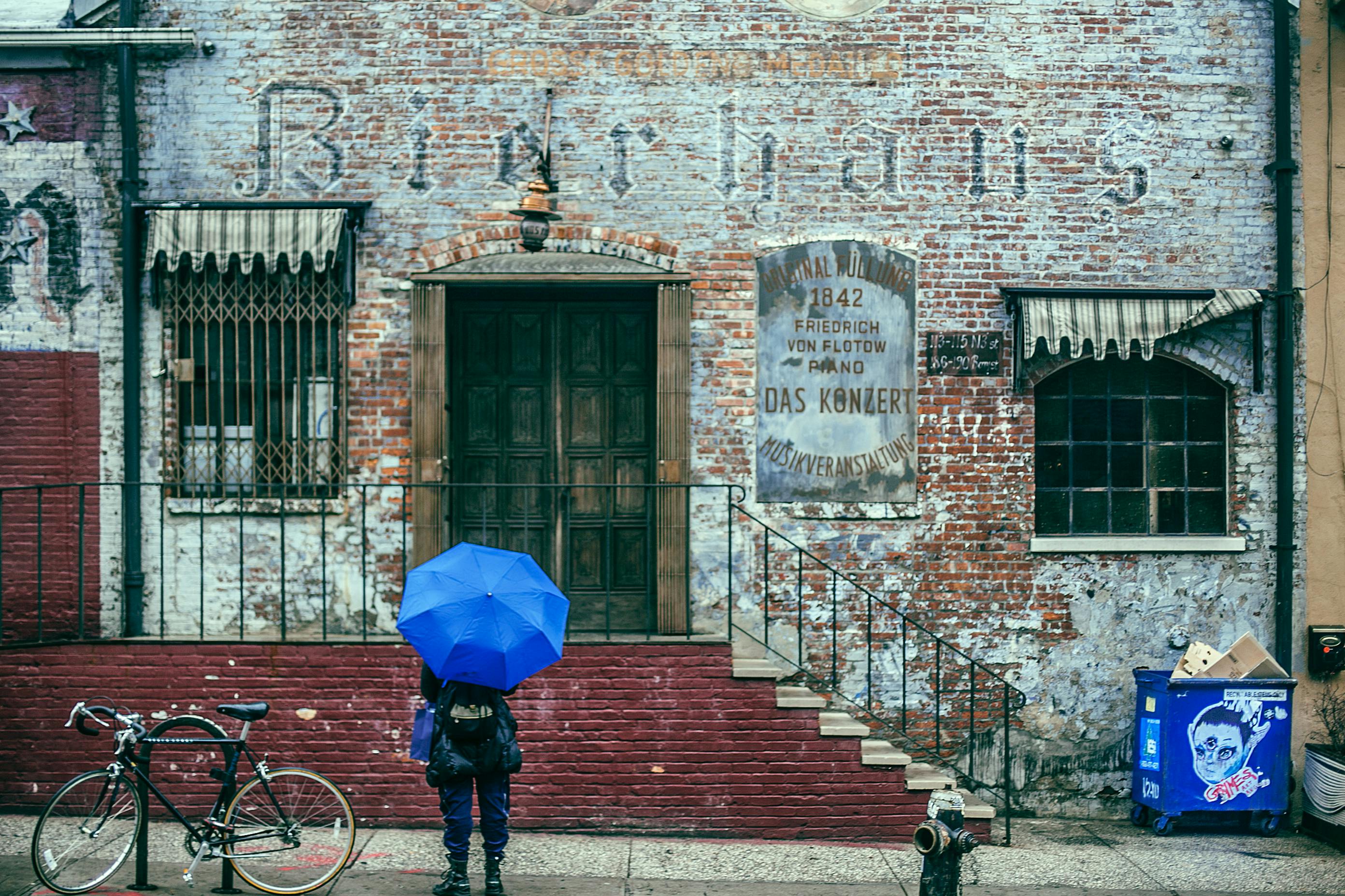 anonymous tourist with umbrella exploring city old district on rain day