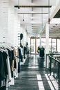 宽敞的现代时尚精品店内，架子上挂着各种衣服，阳光洒落其间