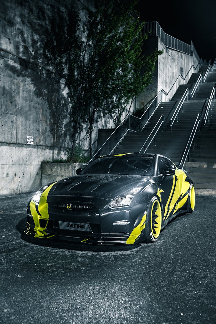 Contemporary Racing Car On Pavement Near Urban Stairs At Night