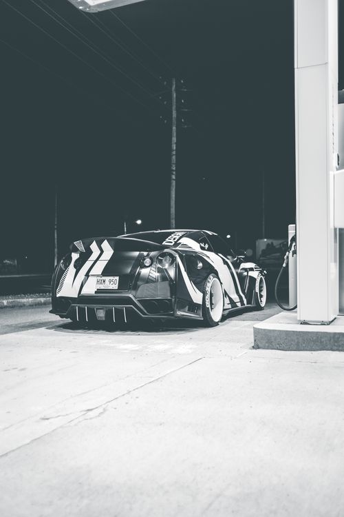 Free Black and white of luxury sports car with ornament on pavement of petrol station at dusk Stock Photo