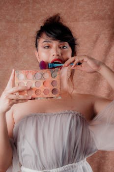 Young woman holding makeup palette and brush, showcasing beauty and artistry skills.