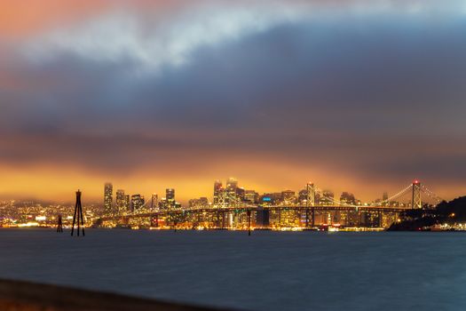 Stunning panoramic view of San Francisco skyline with Bay Bridge and dramatic evening sky.