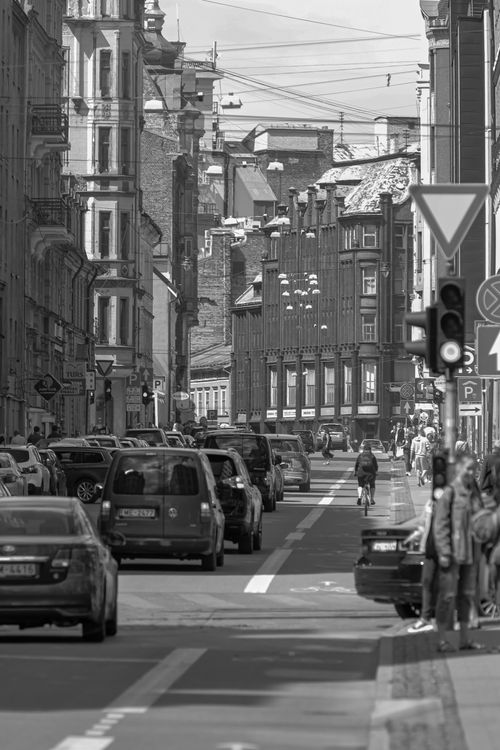 Free Black and white perspective view of asphalt road with automobiles driving along historic city buildings in daylight Stock Photo
