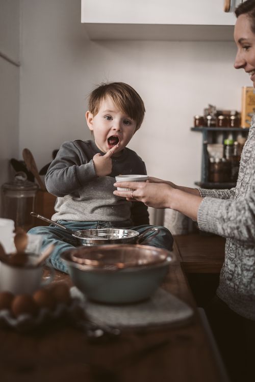 Free A joyful parent and child baking session, capturing a toddler enjoying a sweet moment. Stock Photo