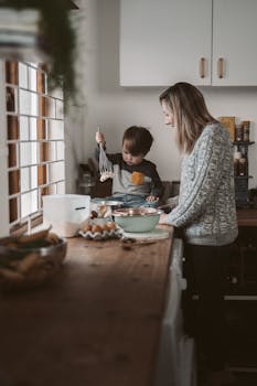 A mother and her child enjoy a bonding moment while baking in their cozy kitchen.