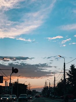 Picturesque sunset sky above busy road with driving cars in modern city in twilight
