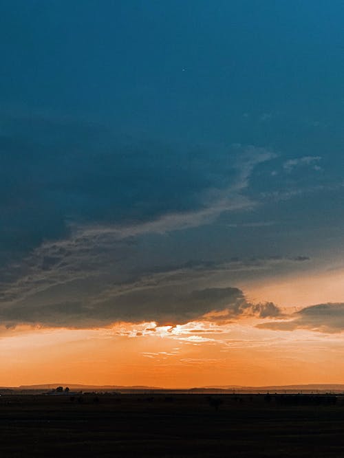 Scenic view of majestic sunset sky with heavy cumulus clouds floating above boundless prairie terrain in twilight