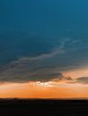 Scenic view of majestic sunset sky with heavy cumulus clouds floating above boundless prairie terrain in twilight