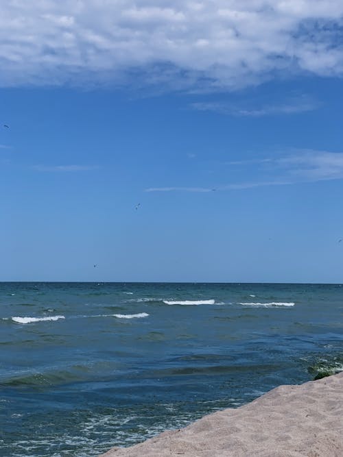 Silent ocean under light blue sky with clouds