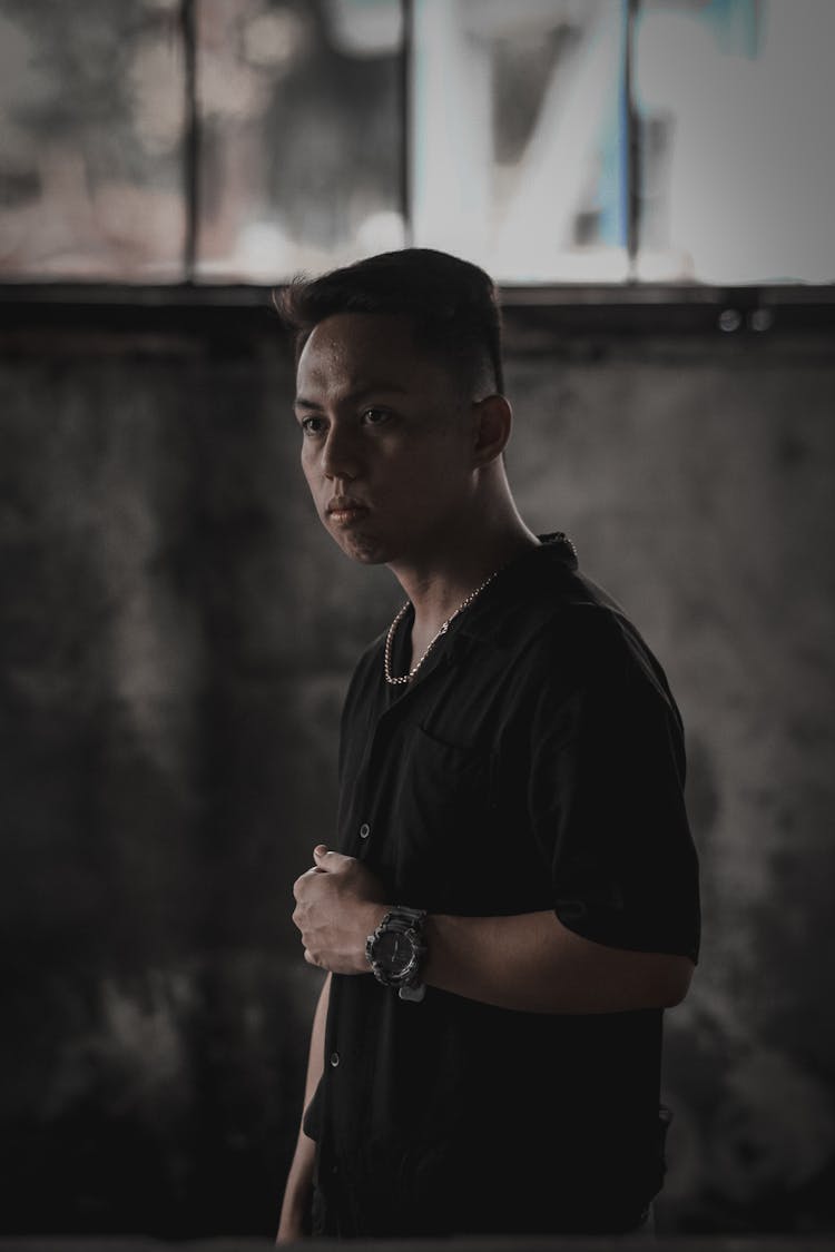 Focused Young Ethnic Man Standing In Dark Abandoned Building And Looking Away