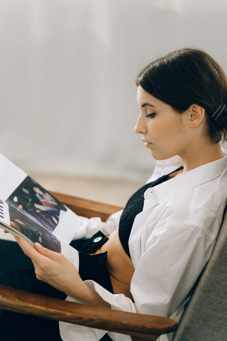 Woman Reading A Magazine While Sitting On A Chair