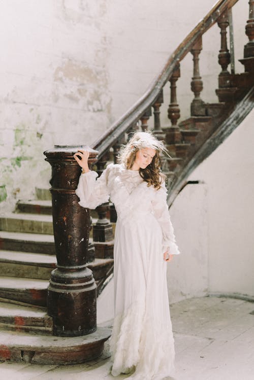 站在灰色的混凝土樓梯上的白色長袖連衣裙的女人