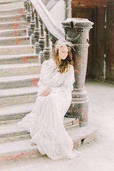一位身着复古白色礼服的新娘，安静地坐在古老的楼梯上，尽显优雅之美