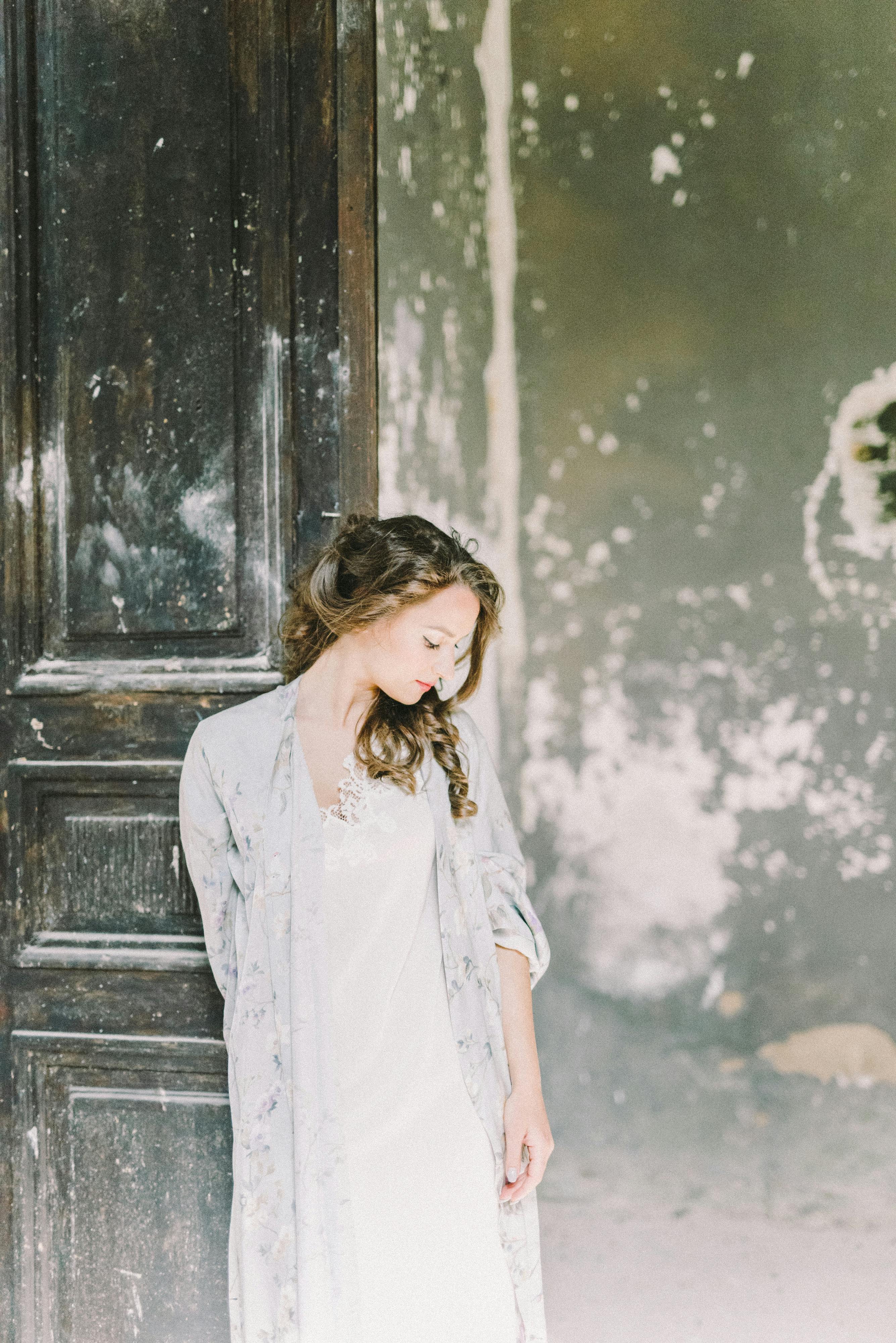 一位黑发年轻女子优雅而宁静地站在质朴的木门旁