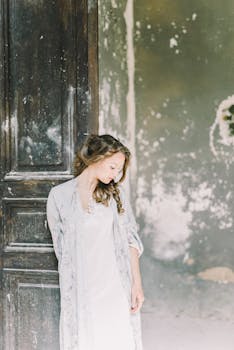 一位黑发年轻女子优雅而宁静地站在质朴的木门旁