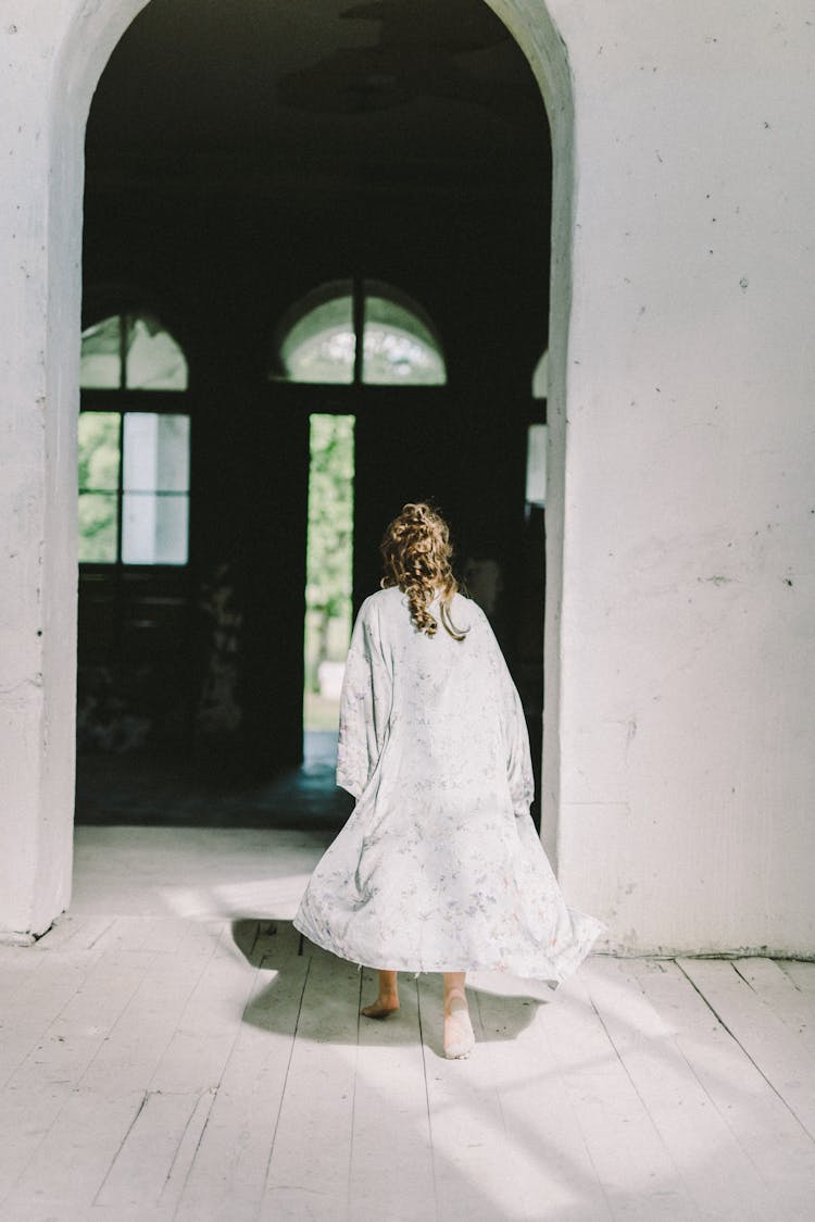 Back View Of A Woman Walking In An Arch Doorway