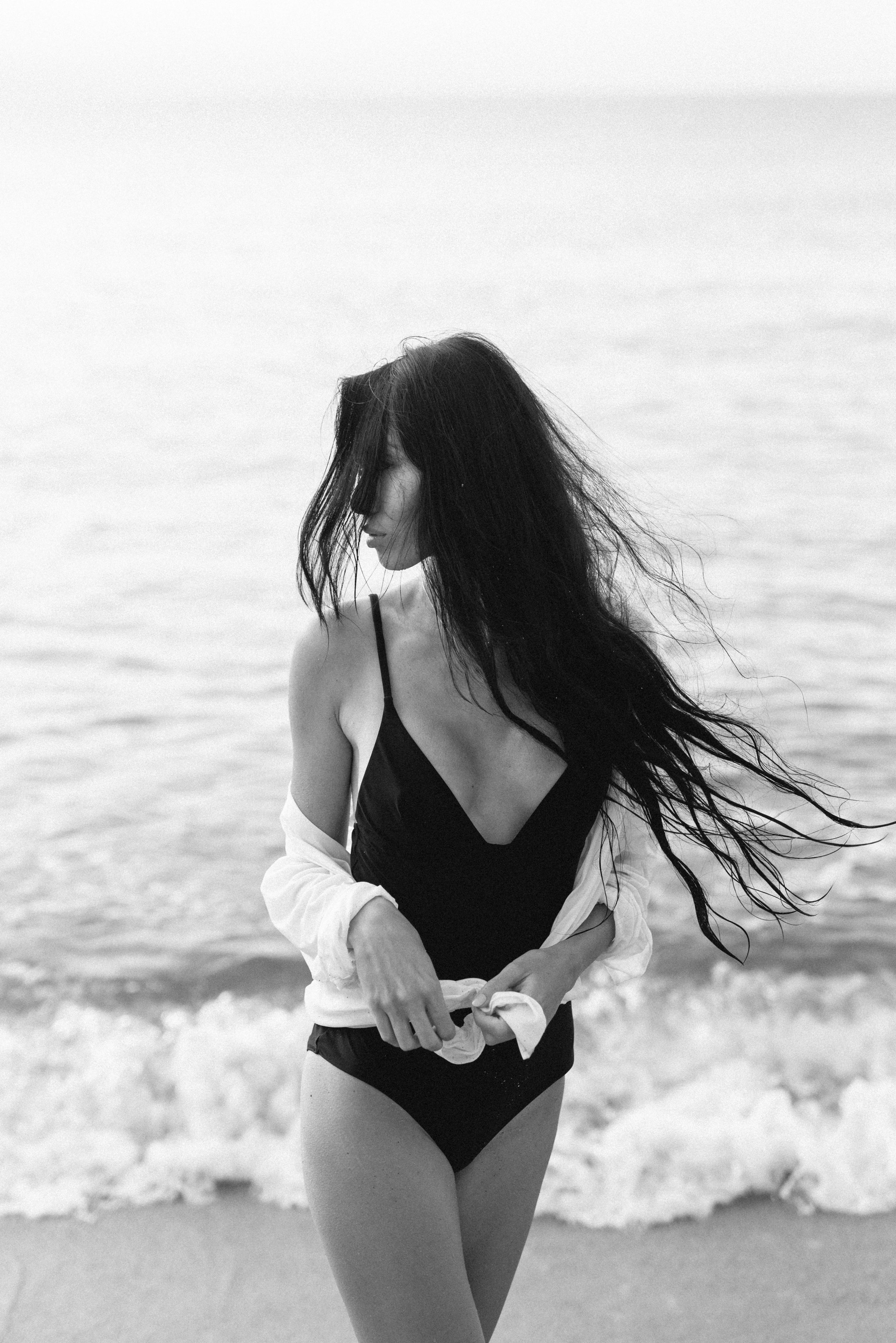 海边一位穿着泳装、留着长发的女子的黑白照片，让人想起优雅与宁静