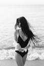 海边一位穿着泳装、留着长发的女子的黑白照片，让人想起优雅与宁静
