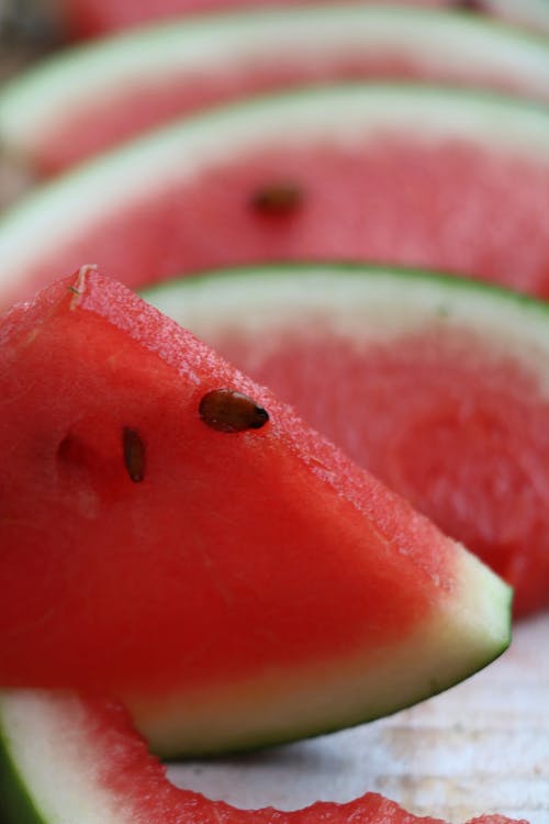 Slices of fresh juicy large fruit with smooth green skin and red pulp with brown seeds