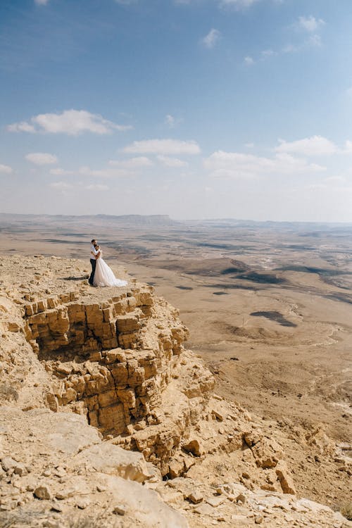 Newlywed Couple Standing on the Edge of a Cliff