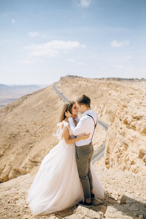 A Man and a Woman Kissing on Brown Rock Formation