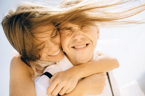 Free Close-up of a happy couple embracing and smiling in bright sunlight. Stock Photo