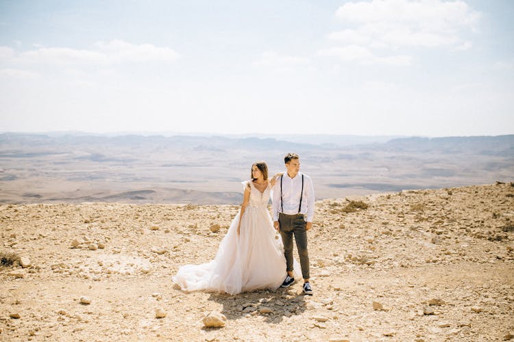 Bride And Groom Standing On Mountain Top