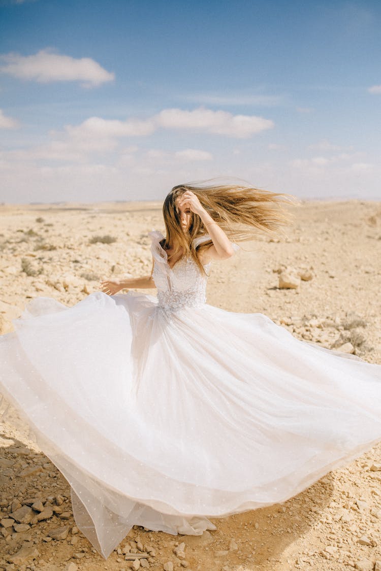 Bride With Her Wedding Dress Blowing In The Wind In The Desert