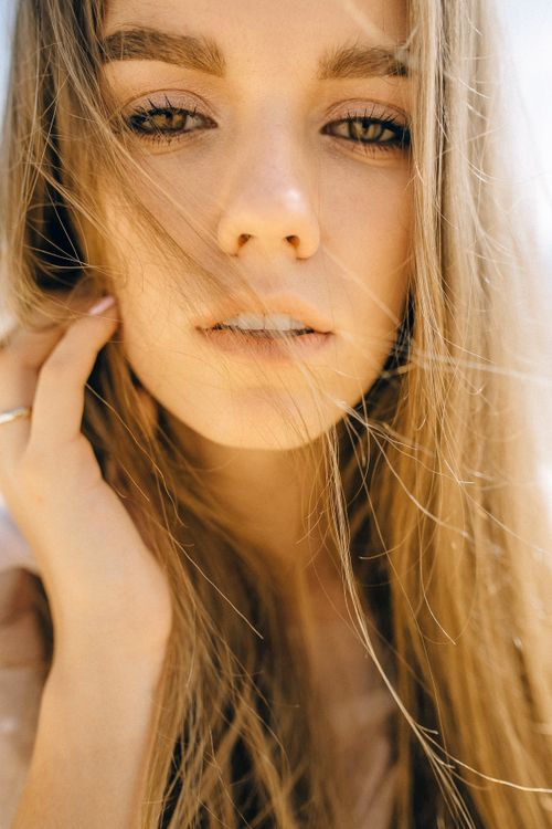 Free A captivating close-up portrait of a young woman with striking features and long blonde hair. Stock Photo
