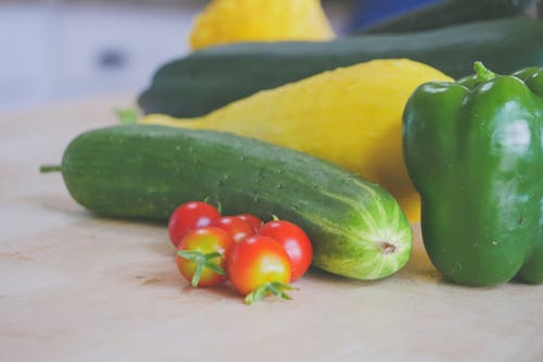 Photograph of Tomatoes Beside a Green Cucumber