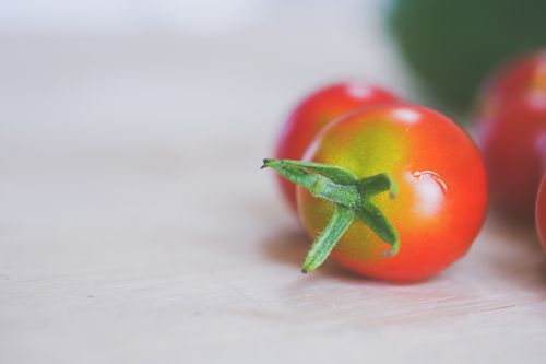 Free Close-up of vibrant cherry tomatoes on a light wooden background, highlighting freshness. Stock Photo
