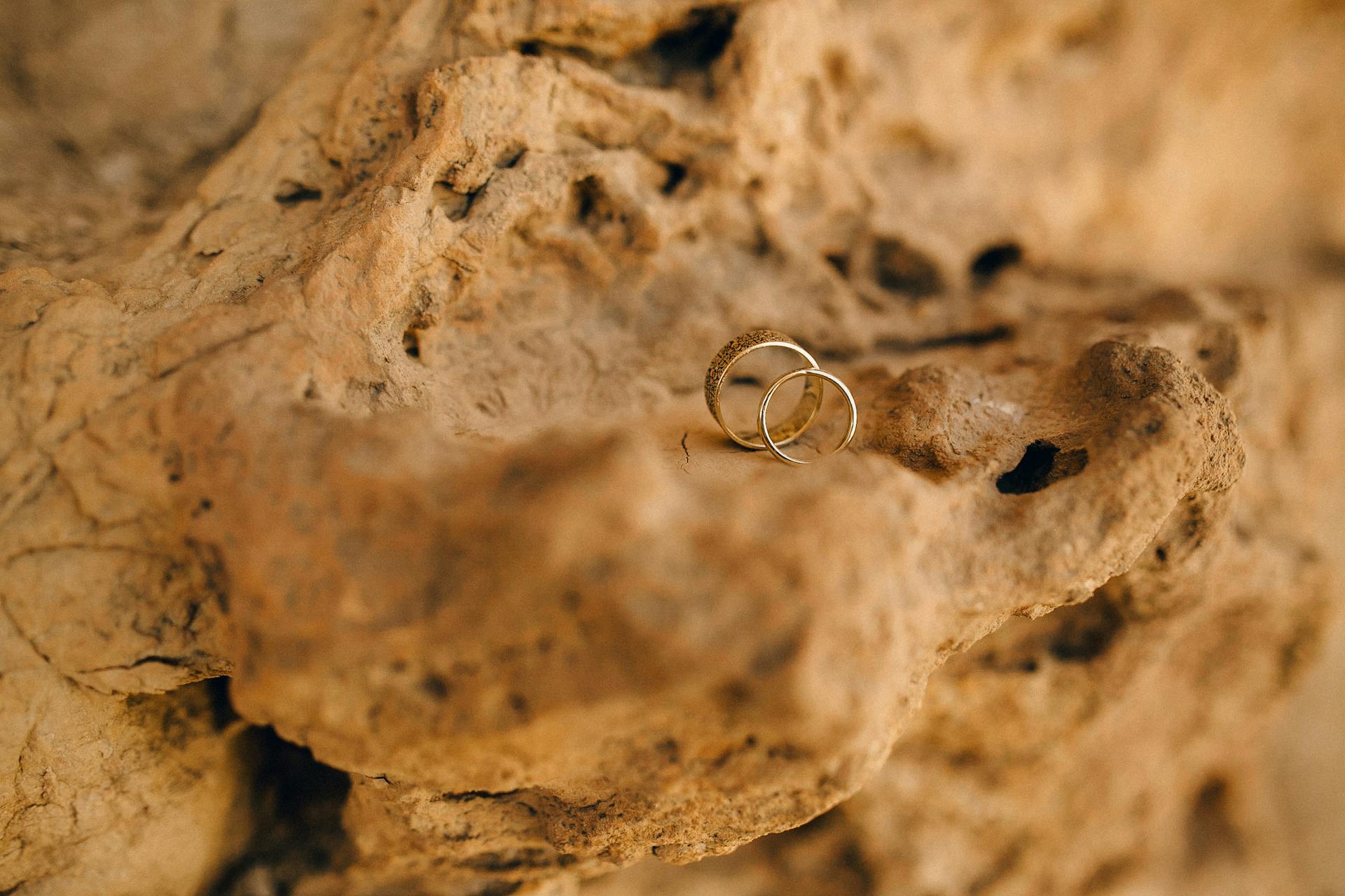 Two elegant wedding rings resting on a textured stone background, symbolizing commitment.