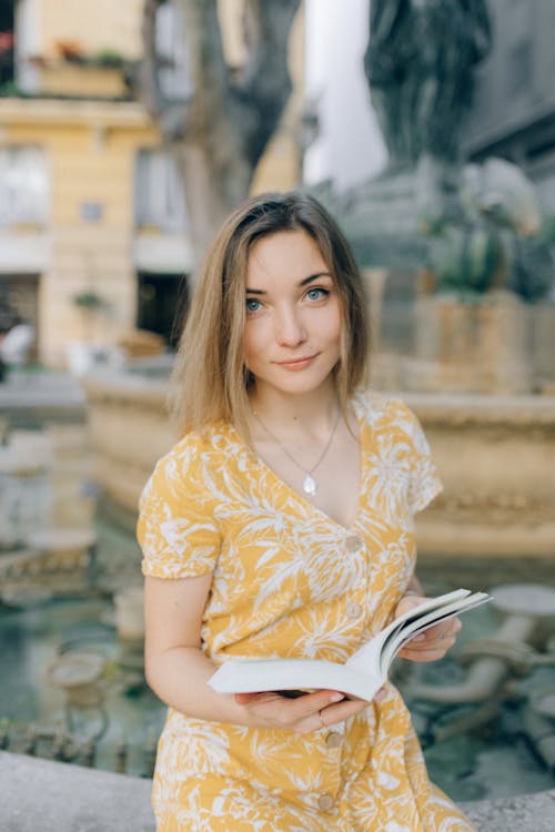 Woman in Yellow Floral Dress Holding a Book