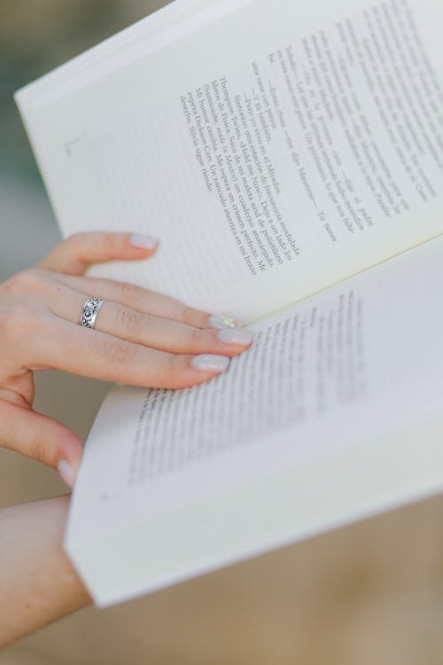 Free  Female Hand with Ring on the Page of a Book Stock Photo