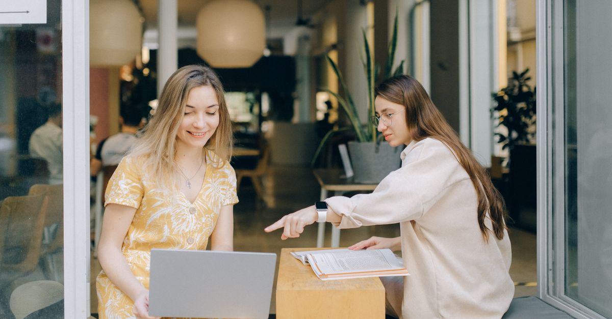 Young professionals laughing while using laptops in a modern co-working space