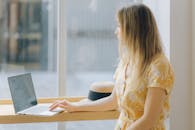 Woman in Yellow Floral Dress Using Her Laptop