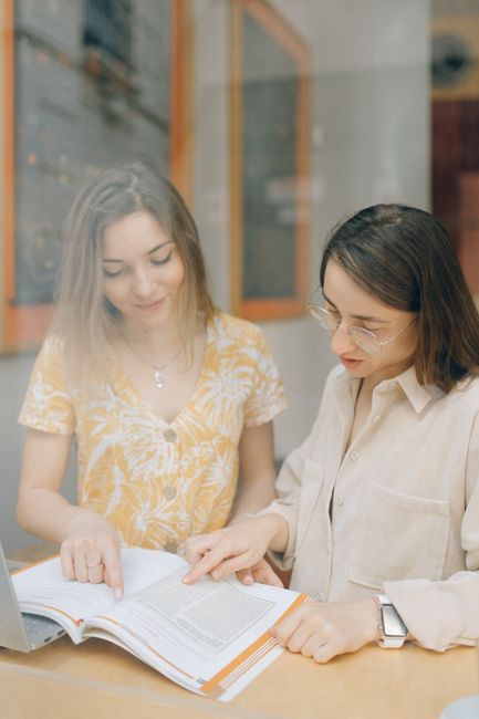 Dos chicas estudiando juntas con libros en la residencia