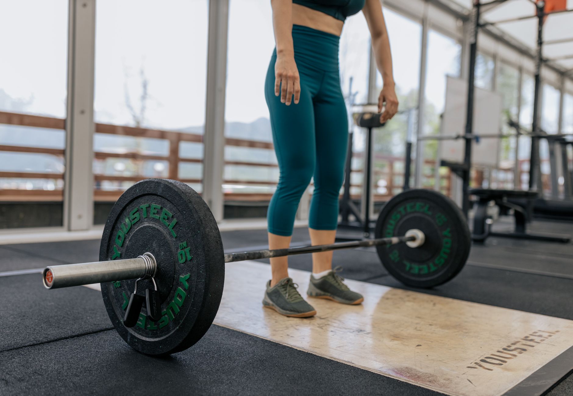 Female athlete preparing to lift a heavy barbell in a gym, showcasing fitness and strength.